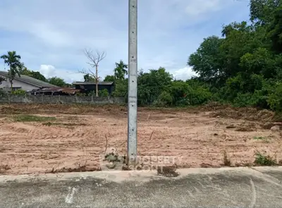 Vacant land plot with potential for development, surrounded by greenery and clear skies.
