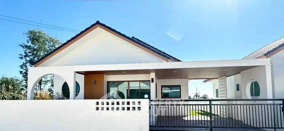 Modern single-story house with sleek design and spacious carport under clear blue sky.