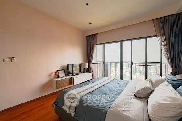 Spacious bedroom with large windows offering stunning city views.