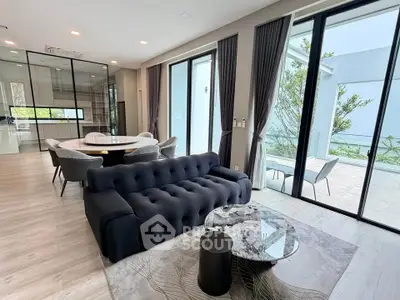 Modern living room with elegant furniture and large windows opening to a patio.