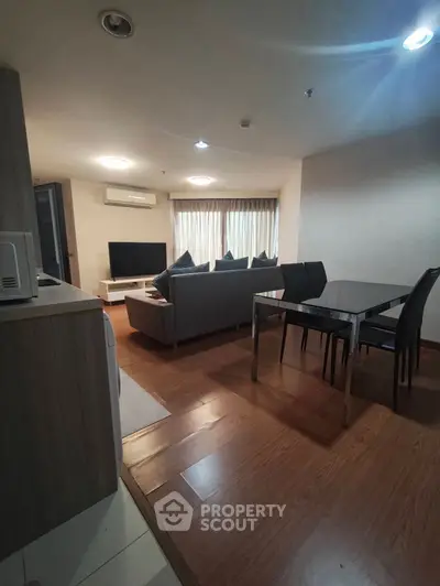 Modern living room with sleek furniture and wooden flooring, featuring a cozy dining area.