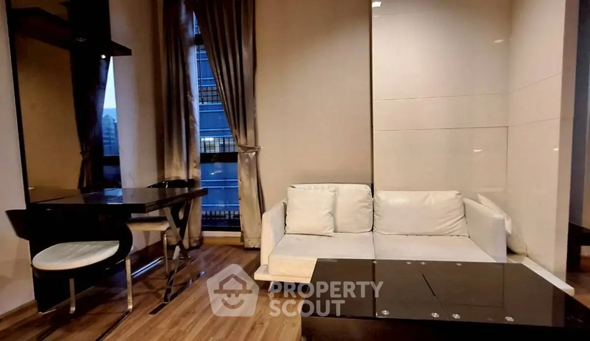 Modern living room with sleek furniture and large windows offering city views.