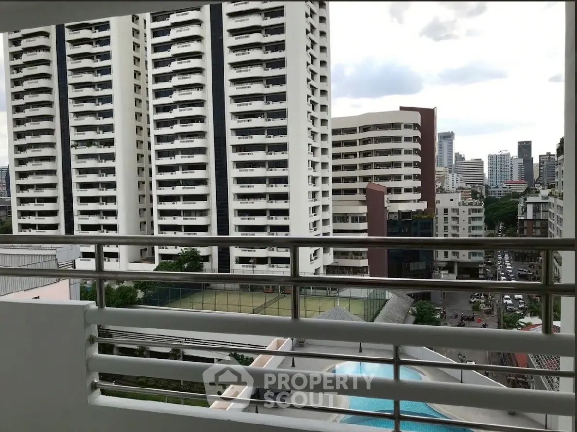 Stunning cityscape view from a modern balcony overlooking pool and tennis court.