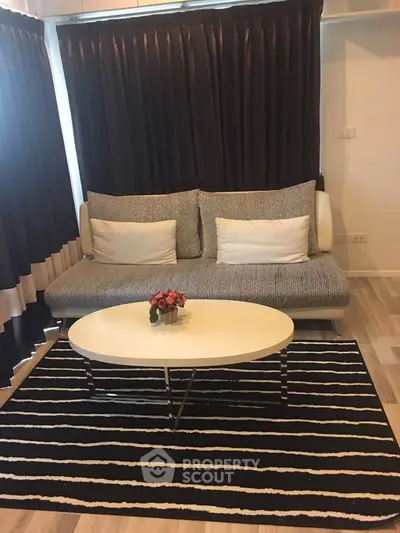 Modern living room with stylish sofa and coffee table, featuring elegant curtains and a chic striped rug.