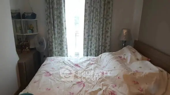 Cozy bedroom with floral curtains and bedding, inviting natural light.