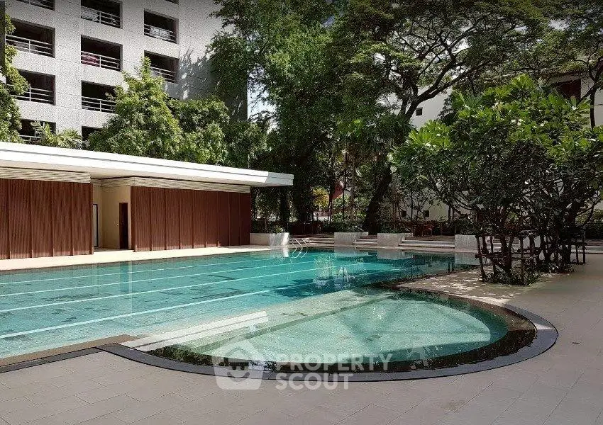 Luxurious residential pool area surrounded by lush greenery and modern architecture.