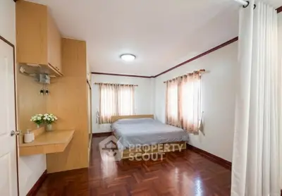 Spacious bedroom with wooden flooring and natural light