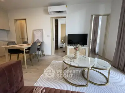 Modern living room with stylish furniture and open layout, featuring a dining area and TV setup.