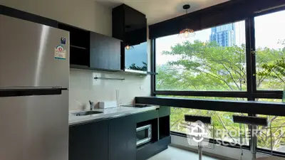 Modern kitchen with large windows and stainless steel appliances overlooking greenery