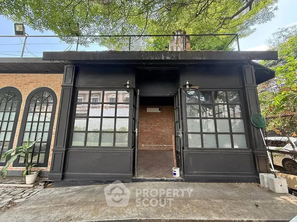 Charming rustic exterior with arched windows and lush greenery, perfect for a cozy retreat or creative studio.