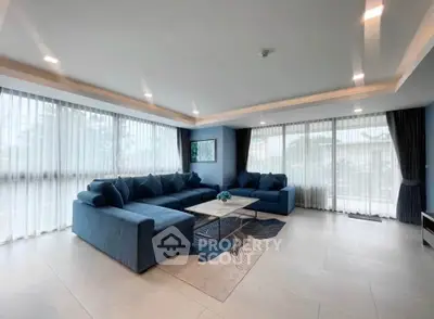 Spacious living room with modern blue sofas and large windows for natural light.