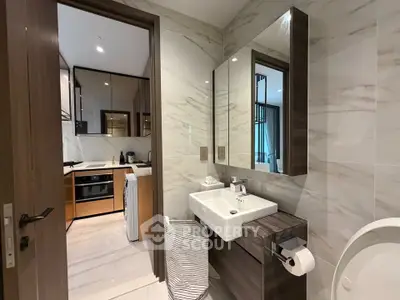 Modern bathroom with sleek design and view into a stylish kitchen