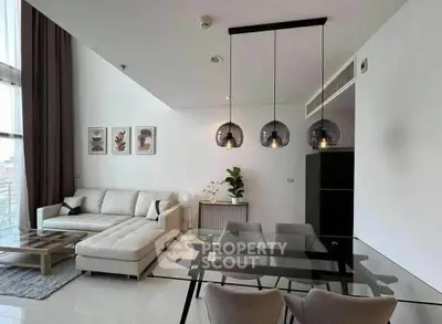 Modern living room with elegant glass dining table and cozy sectional sofa.