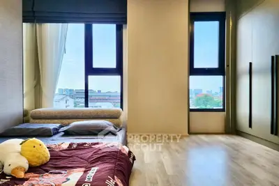 Spacious bedroom with large windows and city view, featuring modern decor and cozy bedding.