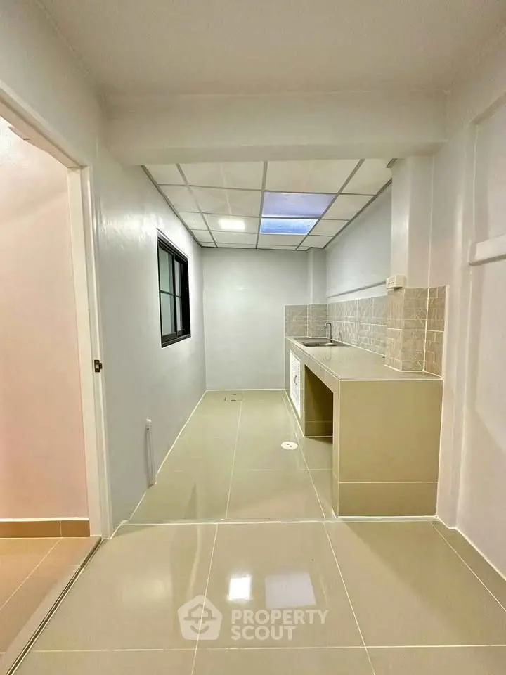 Modern kitchen with sleek tile flooring and built-in washing machine, featuring a minimalist design.