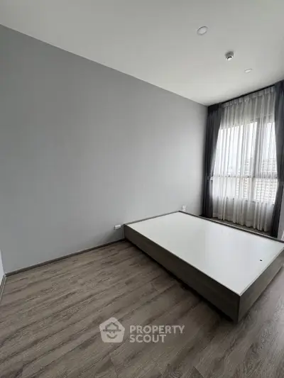 Spacious bedroom with modern flooring and large window for natural light