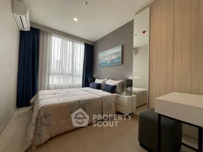 Modern bedroom with stylish decor and large window offering natural light.