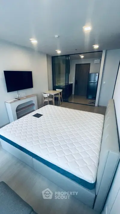 Modern bedroom with stylish decor and wall-mounted TV in a contemporary apartment.