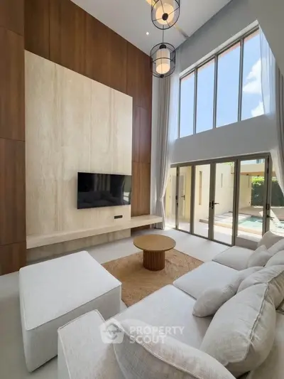 Luxurious modern living room with high ceilings, large windows, and elegant decor overlooking a serene pool area.