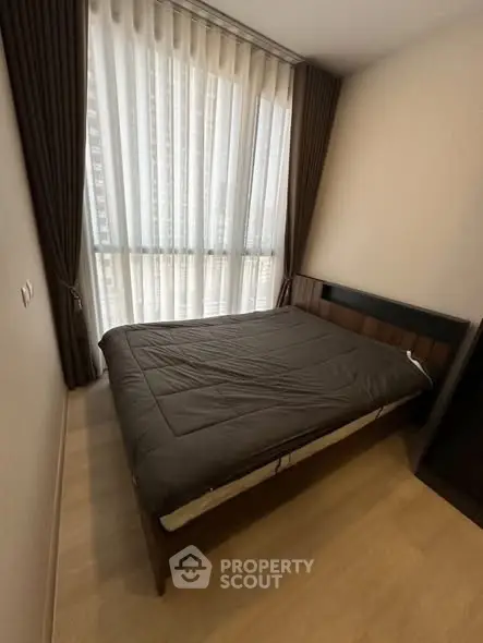 Cozy bedroom with large window and modern furnishings in urban apartment.