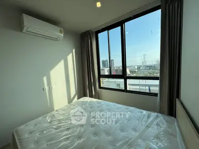 Bright bedroom with large window and city view, featuring air conditioning and natural light.