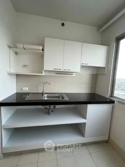 Modern kitchen with sleek black countertop and white cabinets, offering a minimalist design and ample storage.