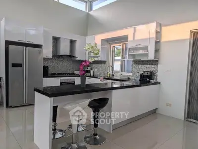 Modern kitchen with sleek design, featuring island and stainless steel appliances.