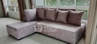 Elegant living room with modern L-shaped sofa and large windows for natural light.