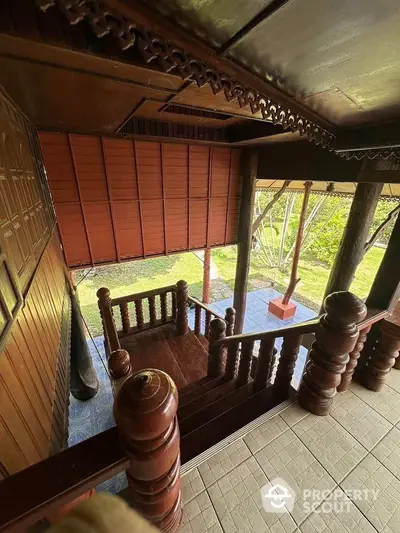 Traditional wooden staircase with intricate carvings leading to a lush garden view.