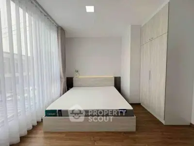 Modern bedroom with minimalist design, featuring a large window and built-in wardrobe.