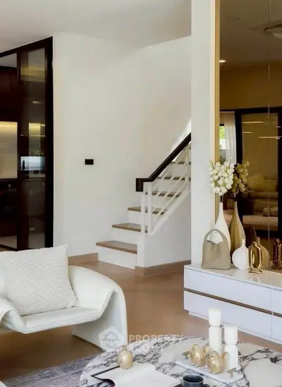 Elegant modern living room with stylish decor and staircase, featuring chic furniture and a marble coffee table.