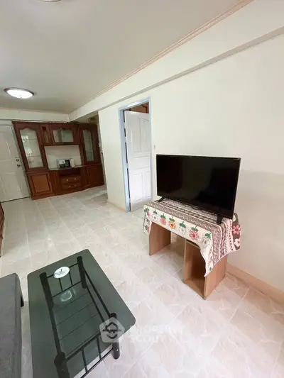 Spacious living room with modern TV setup and elegant wooden cabinetry.