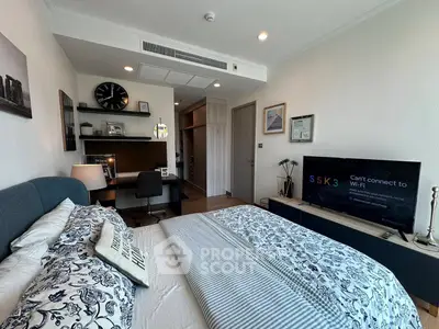 Modern bedroom with stylish decor and workspace, featuring a cozy bed and wall-mounted TV.
