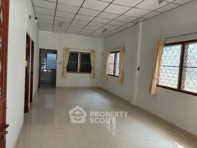 Spacious living room with large windows and tiled flooring, perfect for natural light.