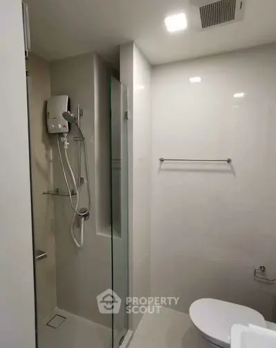 Modern bathroom with sleek shower and toilet in minimalist design.