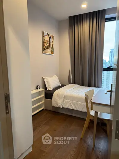 Cozy bedroom with city view, featuring modern decor and wooden flooring.