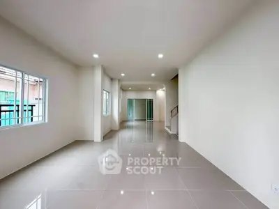 Spacious open-plan living area with glossy tiled floors and ample natural light.