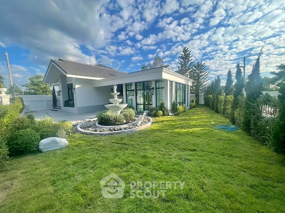 Stunning modern home with lush garden and elegant fountain under a vibrant sky.
