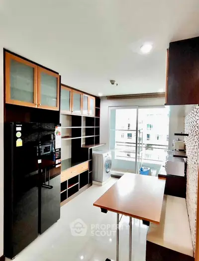 Modern kitchen with sleek black appliances and open layout, featuring a washing machine and ample storage.