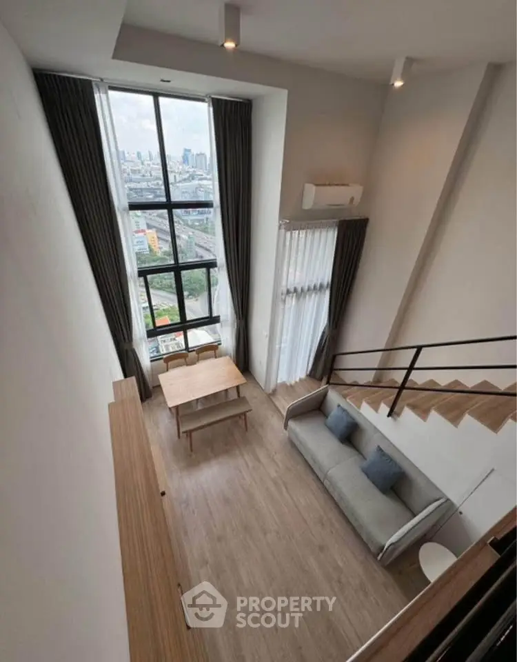 Modern loft apartment with high ceilings and city view, featuring a cozy living area and stylish decor.