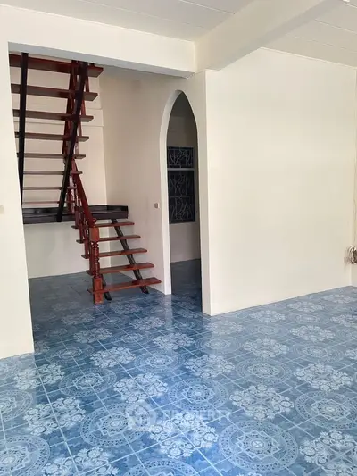 Spacious interior with unique blue patterned flooring and elegant wooden staircase