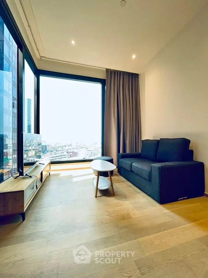 Modern living room with large window offering stunning city view, featuring sleek furniture and natural light.