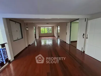 Spacious empty room with polished wooden floors and large windows