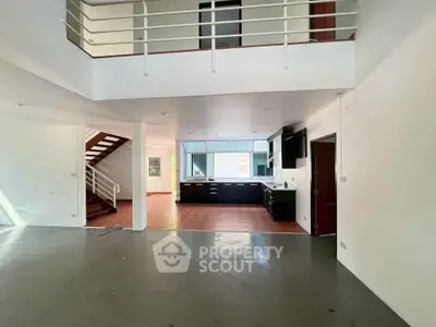 Spacious open-plan living area with modern kitchen and staircase in a contemporary home.