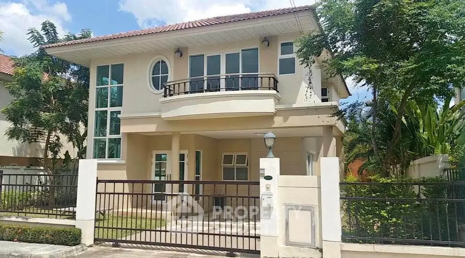 Charming two-story house with a gated entrance and lush greenery