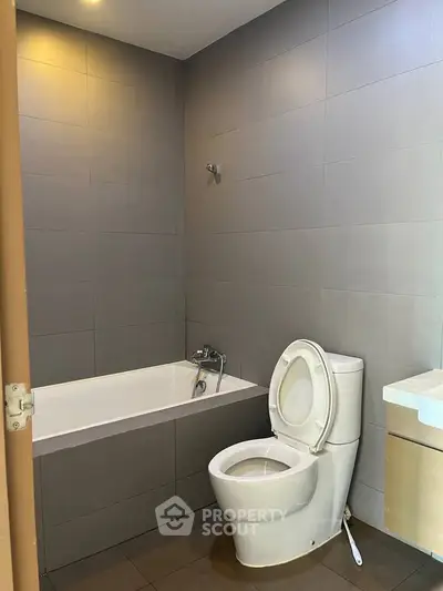 Modern bathroom with sleek design featuring a bathtub and toilet in a minimalist setting.
