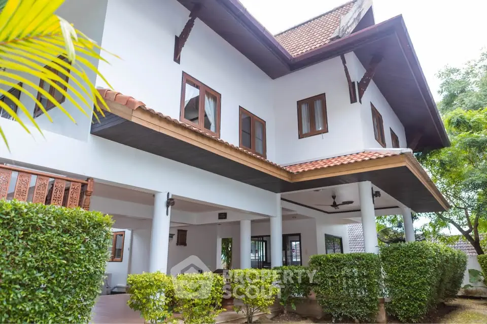 Charming two-story house with lush greenery and traditional architectural design.