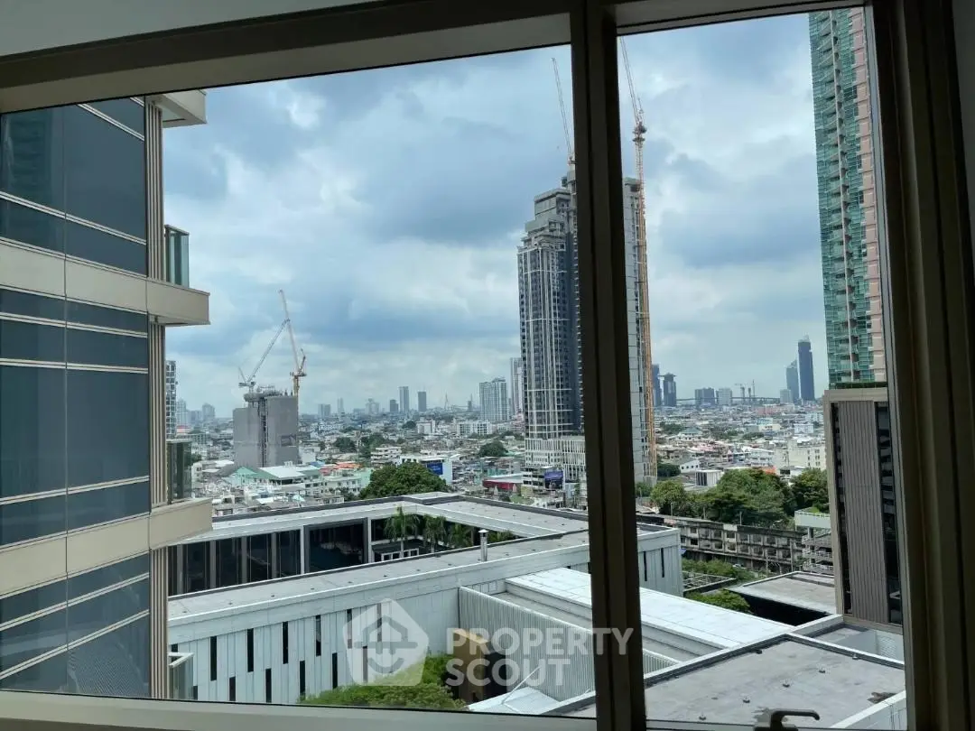 Stunning cityscape view from a high-rise apartment window, showcasing urban skyline and construction cranes.