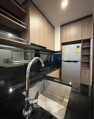 Modern kitchen with sleek black countertops and stainless steel appliances in a stylish apartment.