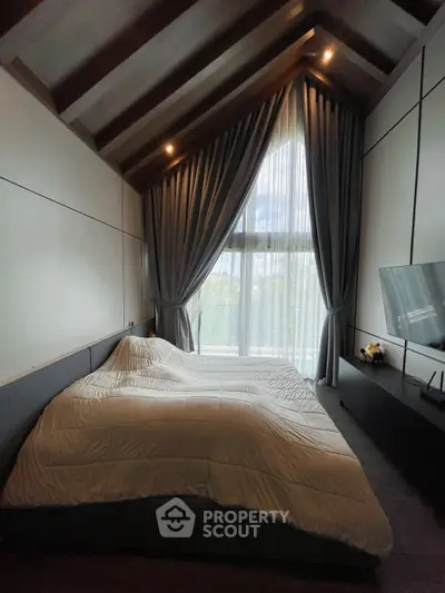 Luxurious bedroom with vaulted ceiling and large window, featuring elegant drapes and modern furnishings.